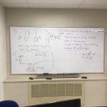 A white board with physics work written on it.